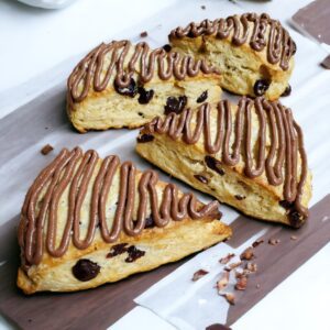 Chocolate-drizzled scones with raisins on board.