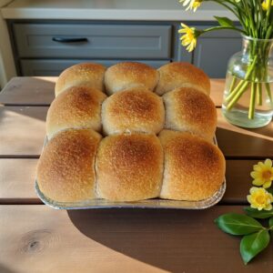 Freshly baked bread rolls by yellow flowers.