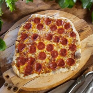 Pepperoni pizza on wooden board, green leaves.
