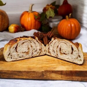 Sliced bread on wooden board, pumpkins background.