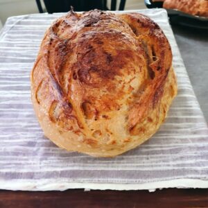 Crusty round loaf of bread on cloth.