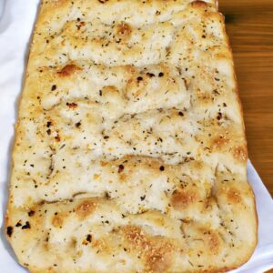Seasoned focaccia bread on a white cloth.