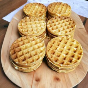 Stacks of round waffles on wooden platter.