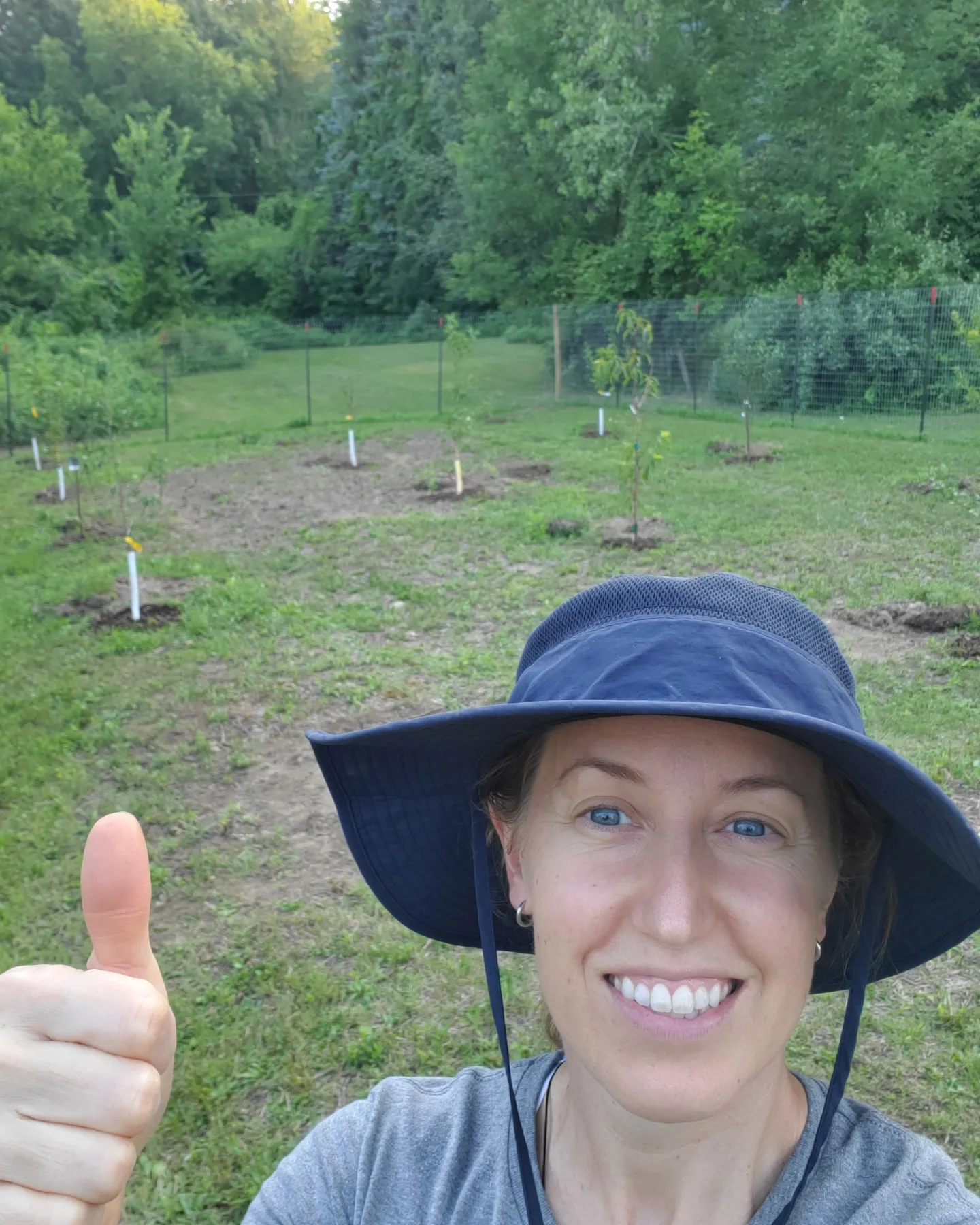 Person giving thumbs up in garden.