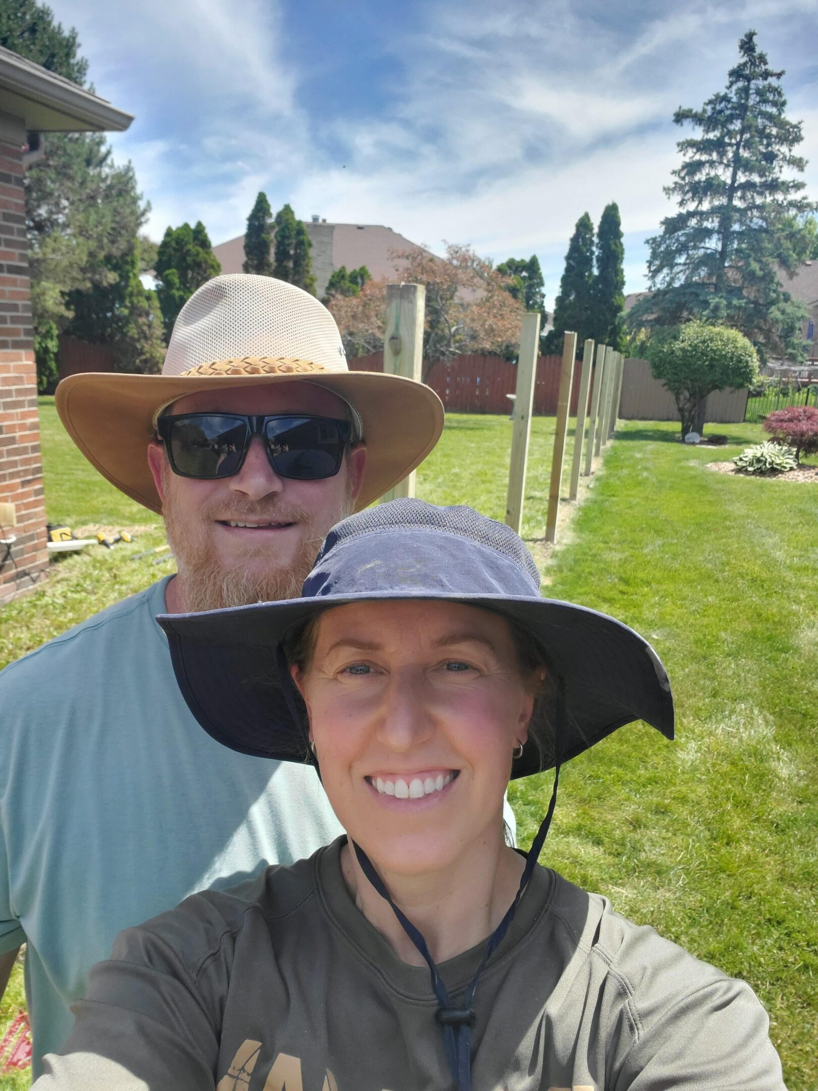 Couple smiling outdoors with sun hats.