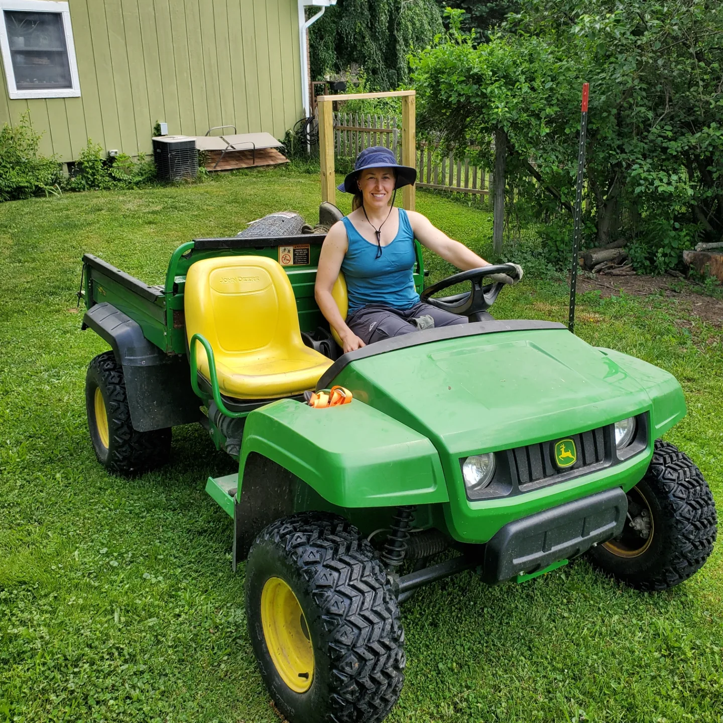 Person sitting on green utility vehicle outside.